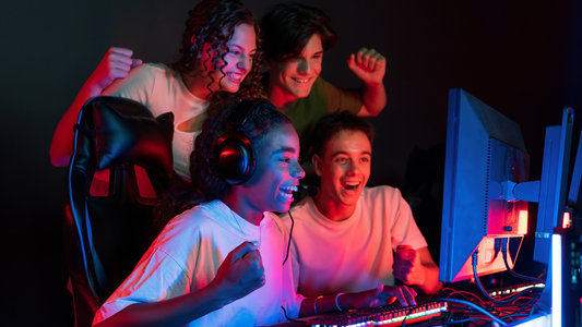 Group of excited teens gaming on PCs with RGB lighting, wearing headsets and gaming gear