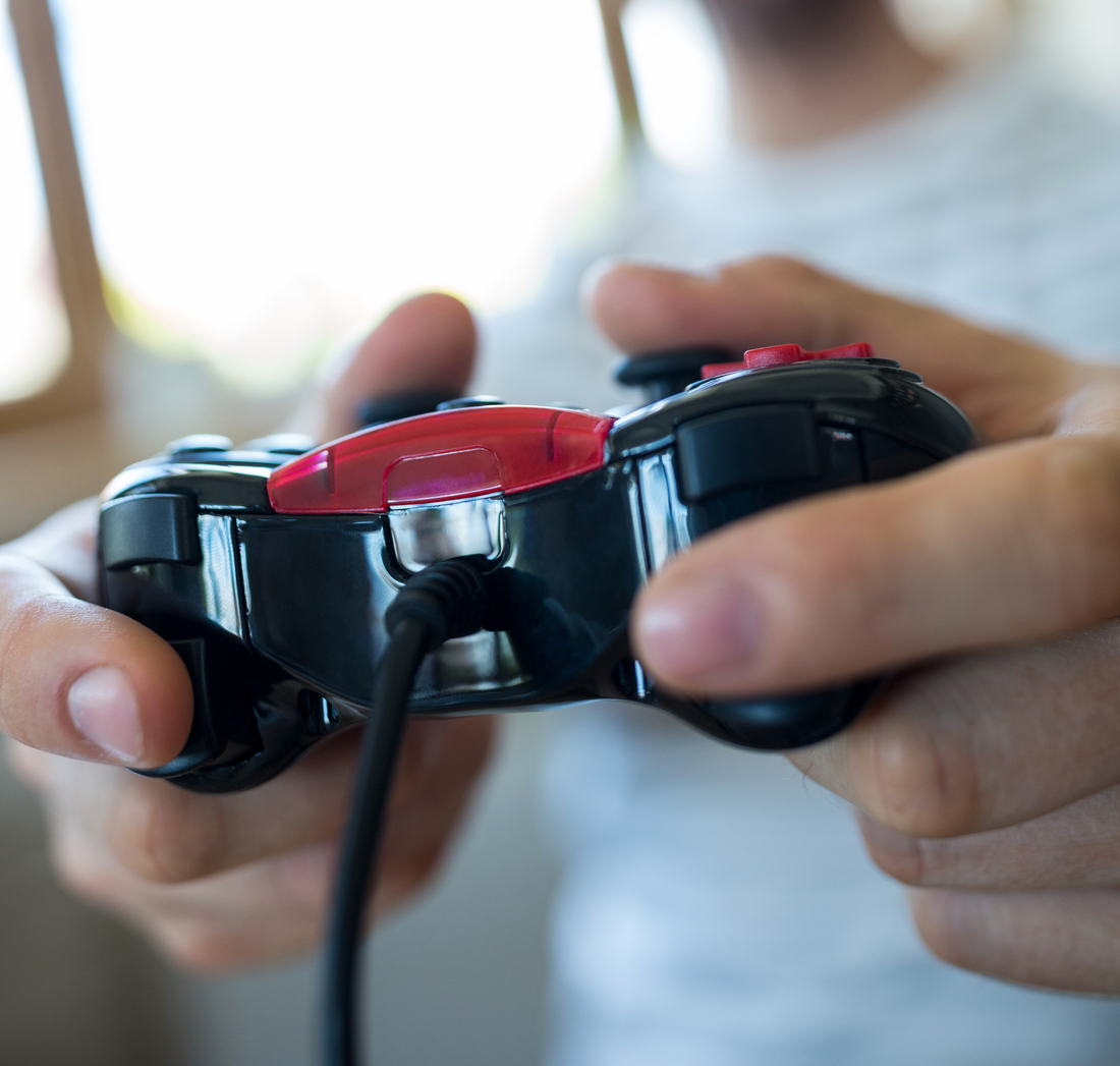 Close-up of hands holding a wired gaming controller, focused on gameplay.