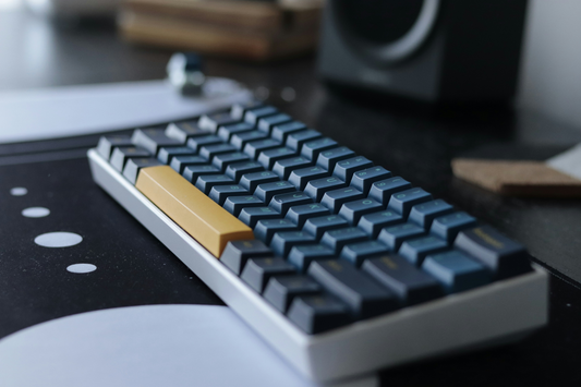 Close-up of a compact mechanical keyboard with blue and yellow keycaps on a desk